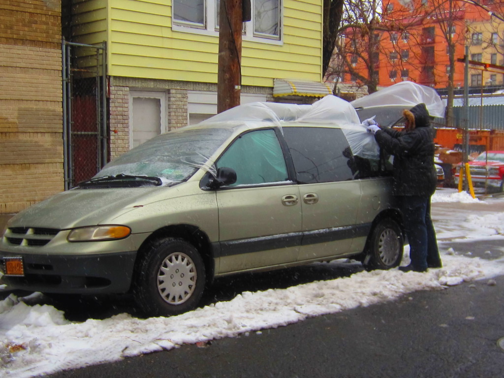 DONNETTA REID SEALS off her vehicle with sheets of plastic ahead of the major snowstorm of the year.  Photo by David Cruz 