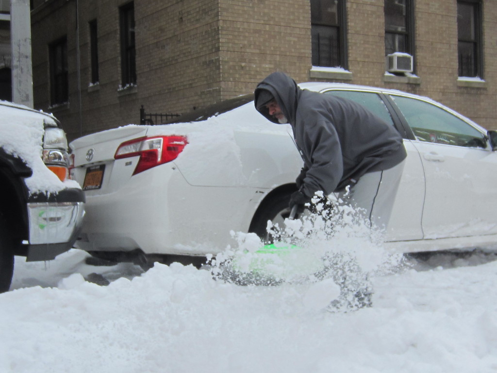 JOSE GUZMAS CLEARS out the mounds of snow that covered his taxi. Photo by David Cruz 