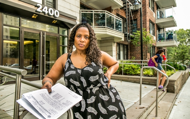 CYNTHIA SCOTT, A TENANT at 2400 Webb Ave. in Kingsbridge, holds up the MCI notice listing the number of projects completed by Goldfarb Properties, the building’s owner.  Photo by Adi Talwar 