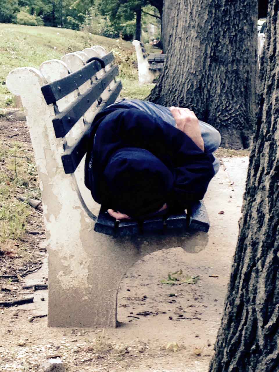 A HOMELESS MAN finds this bench to sleep in one recent afternoon. Photo by David Greene