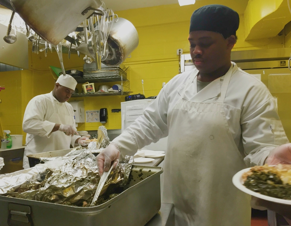 LEARNING THE CULINARY ropes is Aaron Domeny (right), serving up greens at MMCC’s annual pre-Thanksgiving luncheon. Photo by David Cruz 